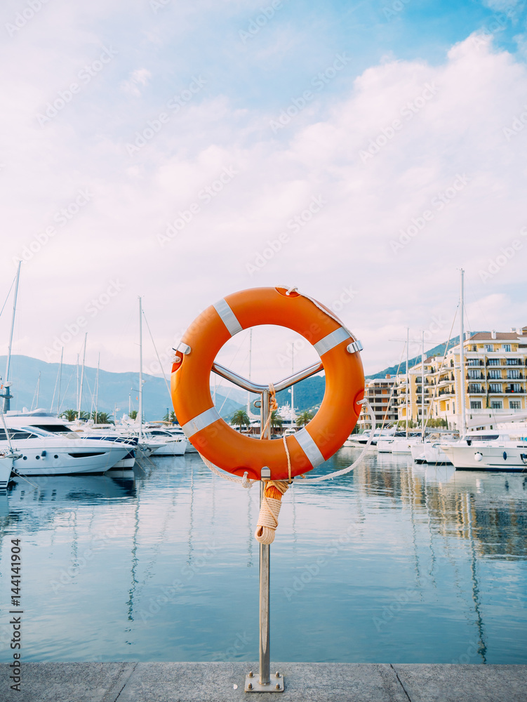 Lifebuoy in the marina for yachts. Red circle on the boat dock. Porto Montenegro, Montenegro.