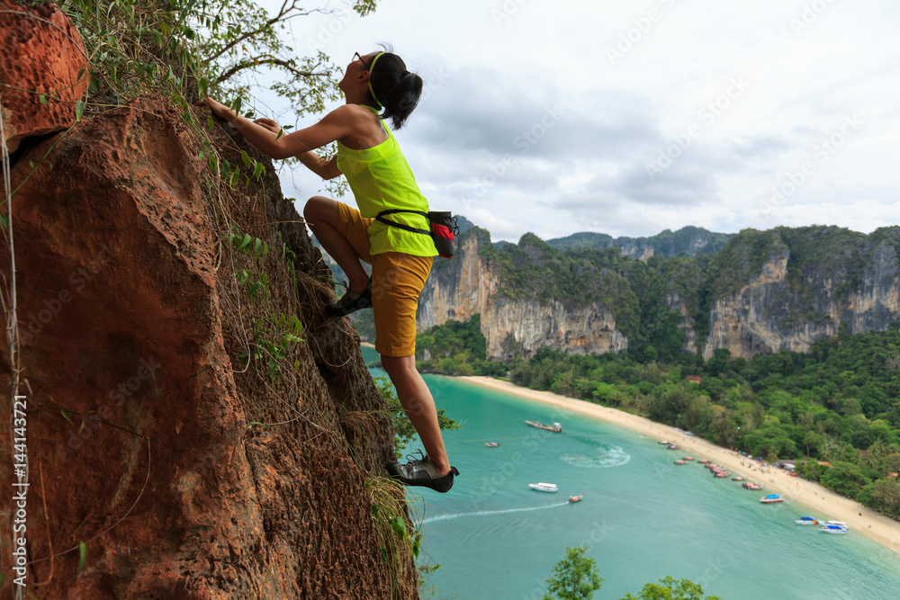 Naklejka premium free solo woman rock climber climbing at seaside cliff