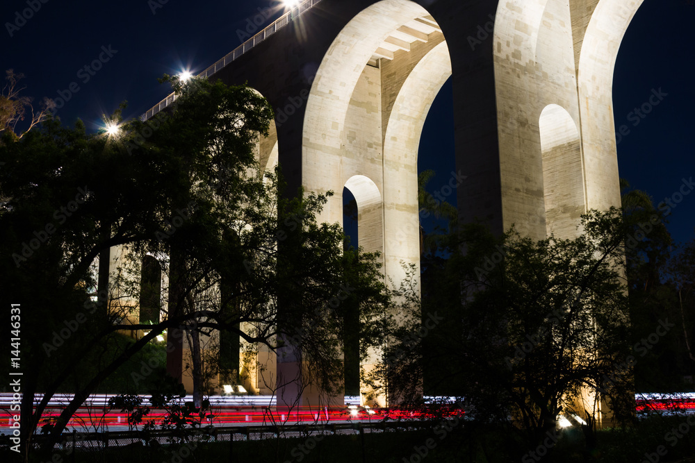 Fototapeta premium Night view of the arches of the Cabrillo bridge in San Diego, California, with car trails on the 163 freeway. 