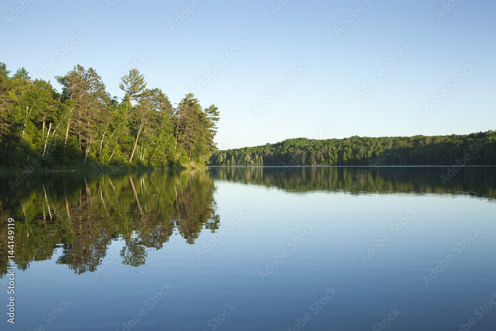 Calm northern Minnesota lake with pine trees at sunset on a clear day