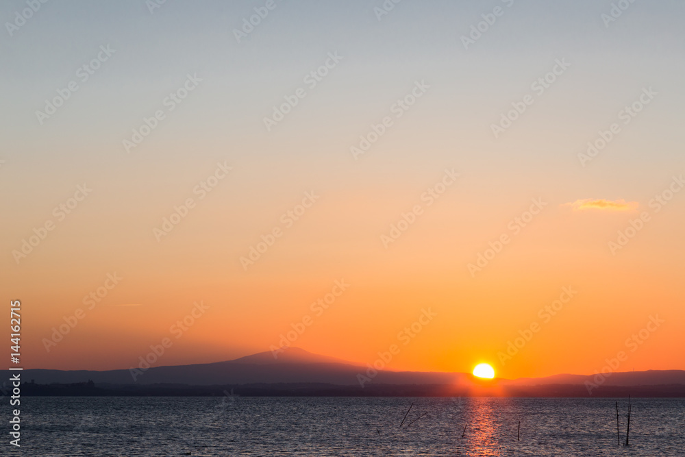A minimalist sunset, with sun reflecting on water and big, spacious sky