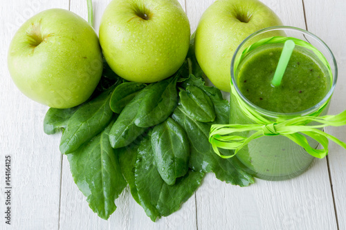 Green smoothie near ingredients for it on white wooden background. Apple, lime, spinach. Detox. Healthy drink.