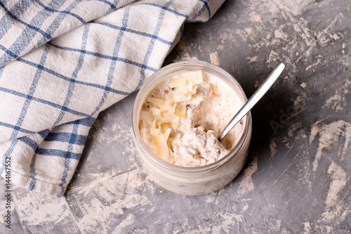Healthy breakfast overnight oats with cocos and banana in a glass jar
