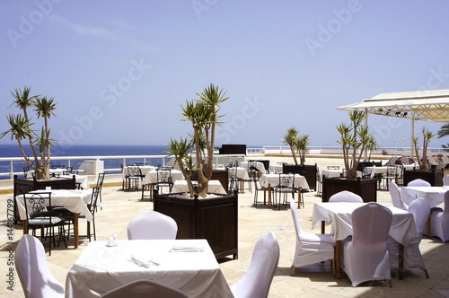 The tables in the outdoor restaurant by the sea. Original interior © yulliash