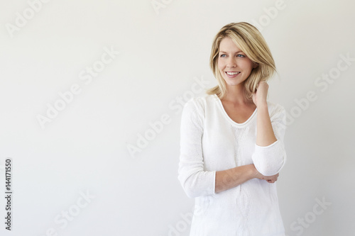 Beautiful blond smiling in studio, looking away