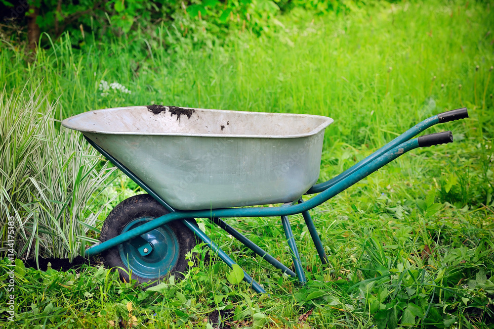 Old wheelbarrow on a green grass field background Old wheelbarrow on a green grass field background