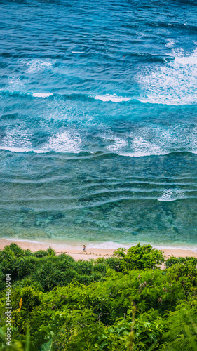 Man walking along of Nunggalan Beach. Big waves rolling on. Uluwatu, Bali, Indonesia