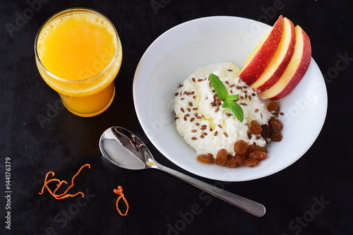 Healthy breakfast: cottage cheese with flax seeds, raisins, fresh apples and a glass of fresh orange juice. Healthy eating concept photo