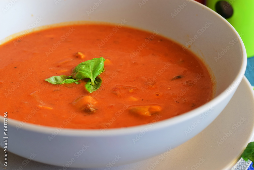 Tomato soup with mussels in a blue bowl on a blue background with bread sticks. Healthy eating concept