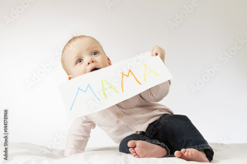Cute baby with poster with a sign Mama. Infant boy holding greeting card for Mothers day.