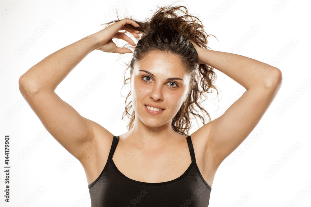 Fototapeta premium beautiful young woman adjusts her curly hair in a ponytail