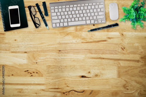 Office desk table with computer, supplies,analysis chart, ipad,smartphone,coffee cup on wooden background. Top view with copy space