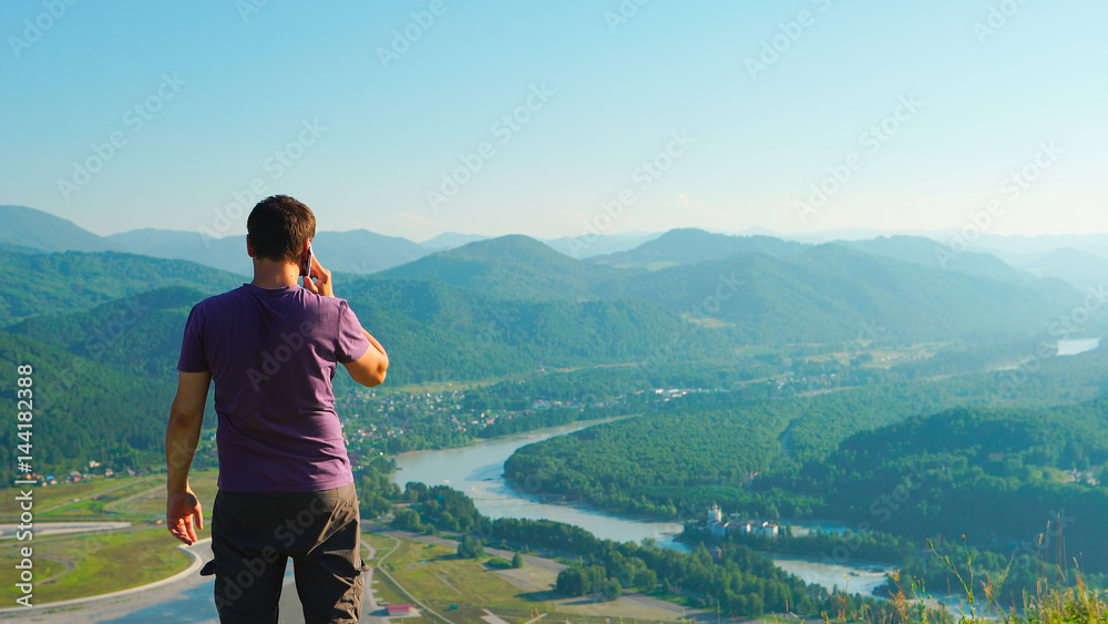 Man talking on a mobile phone on a mountain landscape background Man talking on a mobile phone on a mountain landscape background