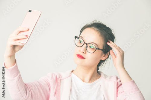 Portrait of beautiful young woman playing her mobile phone,taking selfie.