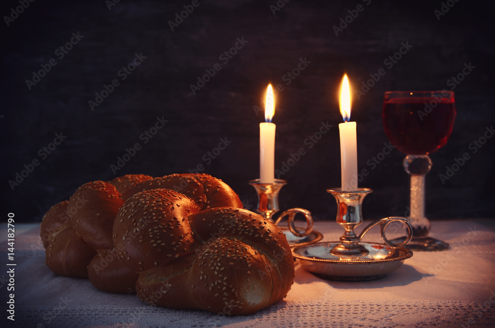 Fototapeta premium Low key shabbat image. challah bread, shabbat wine and candles