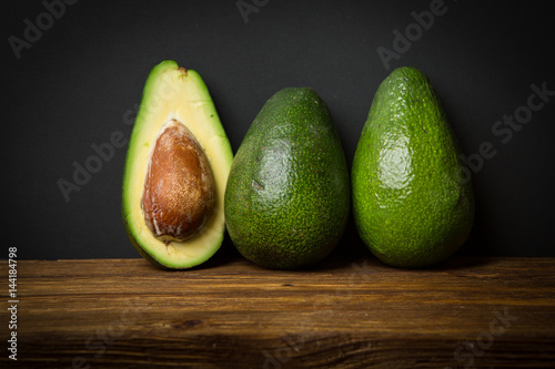 Three fresh avocado on wood background