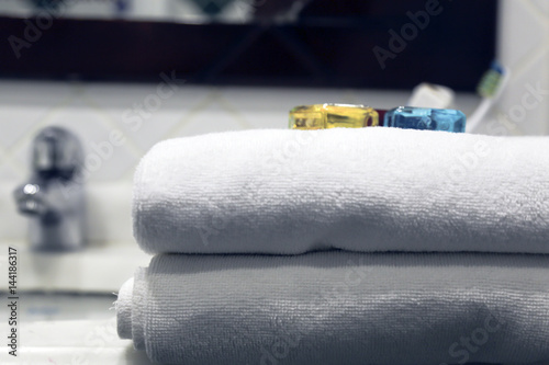 White towel with bottles of shampoo near a sink in a bathroom 