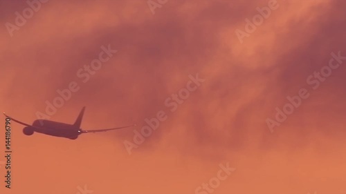 A commercial airplane right aftet takeoff against an orange fiery sunset sky. Nai Yang, Phuket, Thailand. photo