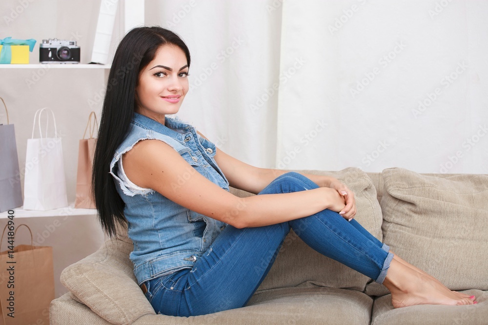 Relaxed casual brunette in blue cardigan and In blue jeans sits on the couch Relaxed casual brunette in blue cardigan and In blue jeans sits on the couch