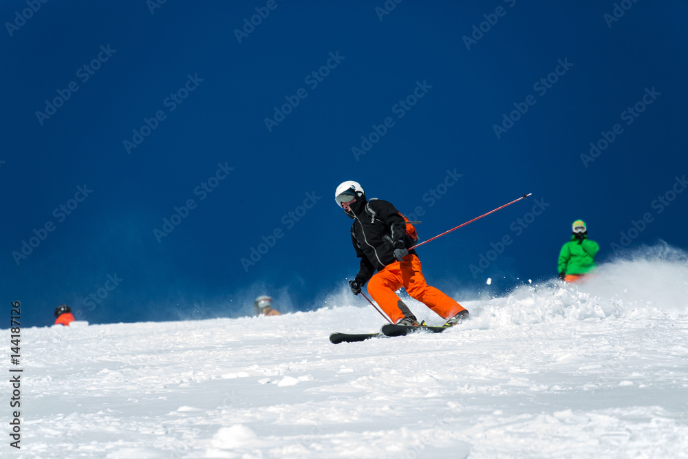 A skier during descent at a ski resort. Beautiful winter landscape with snow-topped mountains.