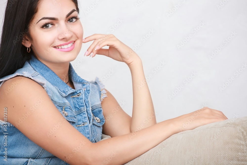 Relaxed casual brunette in blue cardigan and In blue jeans sits on the couch Relaxed casual brunette in blue cardigan and In blue jeans sits on the couch