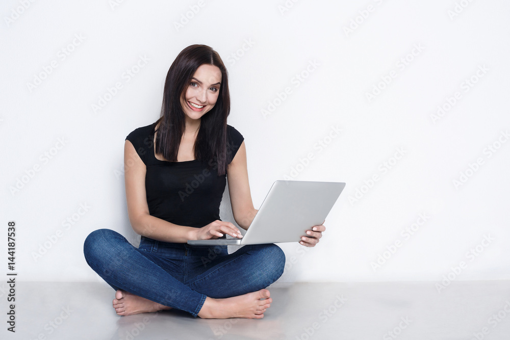 Woman using laptop sitting on the studio floor Woman using laptop sitting on the studio floor
