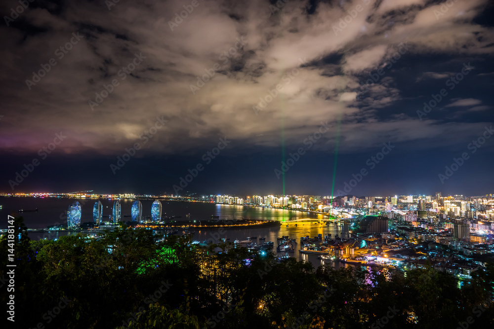 Obraz premium Night view of an artificial Phoenix island and Sanya city illuminated with city lights. View from Luhuitou Park on Hainan Island of China.