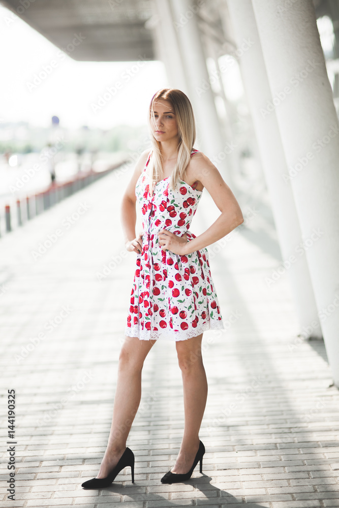 young blonde girl in white and red dress posing in a street young blonde girl in white and red dress posing in a street
