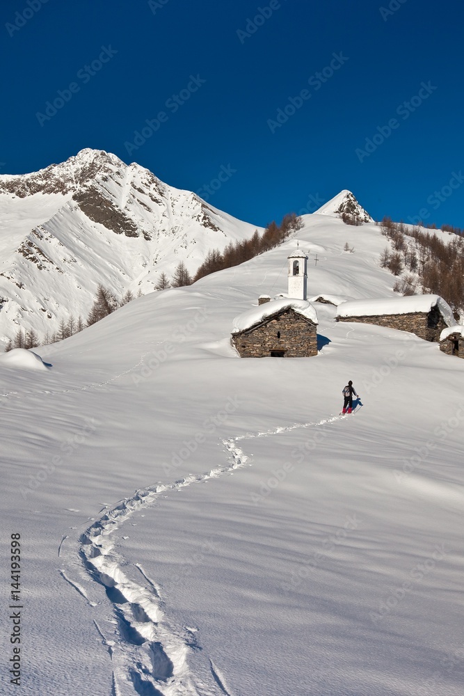 Footsteps in the snow of a hiker with snowshoes trying to reach the Scima Alp. In the background Forcola Peak. Chiavenna. Valchiavenna. Vallespluga. Valtellina. Lombardy. Italy. Europe Footsteps in the snow of a hiker with snowshoes trying to reach the Scima Alp. In the background Forcola Peak. Chiavenna. Valchiavenna. Vallespluga. Valtellina. Lombardy. Italy. Europe
