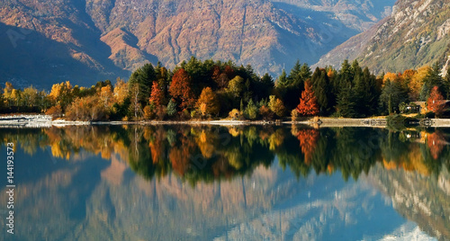 The autumn colors are reflected in the calm waters of Lake Mezzola. Novate Mezzola. Valchiavenna. Vallespluga. Lombardy Italy. Europe