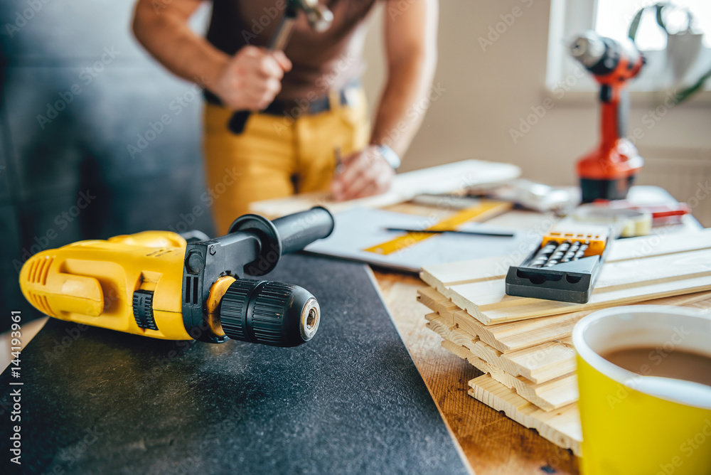 Power drill and Man using hammer in the background