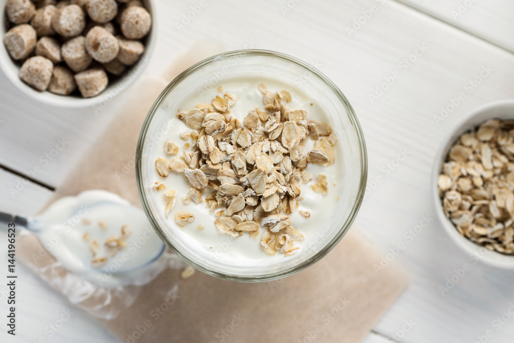 Yogurt with oat flakes on a wooden table, top view Yogurt with oat flakes on a wooden table, top view