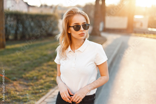 Принти на полотні Young girl in trendy sunglasses and white polo shirt in a spring day at sunset