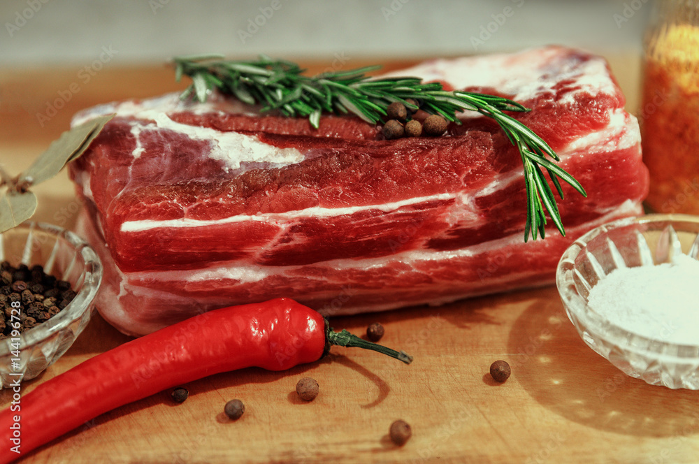 A piece of raw fresh meat with red pepper and spices on a rustic background. Is suitable for steak cooking