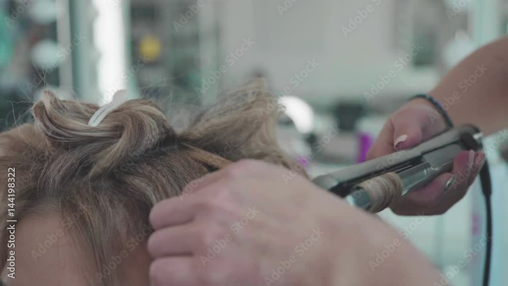 Stylist. Hair stylist making curls on customer hair using electric curler. Beauty saloon. Woman with Long Hairs, hairdresser's hands close up, Barbershop, Hairdressing Salon, Beauty Salon. Stylist. Hair stylist making curls on customer hair using electric curler. Beauty saloon. Woman with Long Hairs, hairdresser's hands close up, Barbershop, Hairdressing Salon, Beauty Salon.
