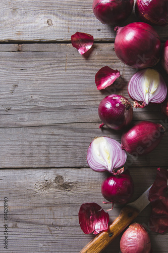 Red onion bulbs lying on an old wooden table.
