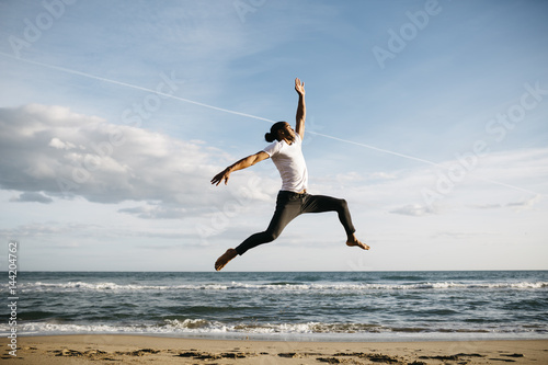 Young man jumping in the air on the beach