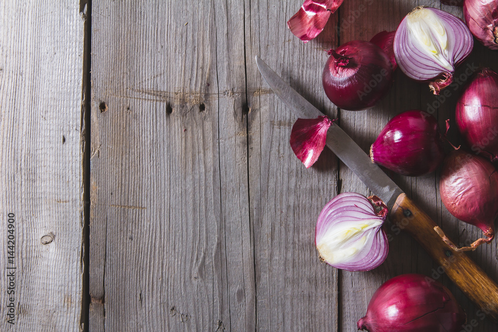 Red onion bulbs lying on an old wooden table. Red onion bulbs lying on an old wooden table.