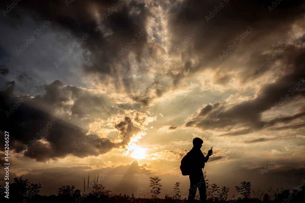 Silhouette man with backpack use smartphone in hands at sunset background, Travel concept.