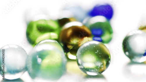 Colorful rolling glass marbles on white background.