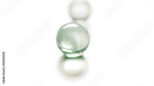 Colorful rolling glass marbles on white background.