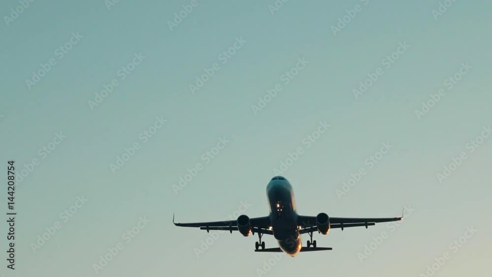 Slow motion dramatic view of slightly unfocused big shiny airplane approaching on side and passing over while landing at early morning time Slow motion dramatic view of slightly unfocused big shiny airplane approaching on side and passing over while landing at early morning time