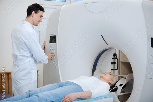 Nice delighted doctor doing tomography examination