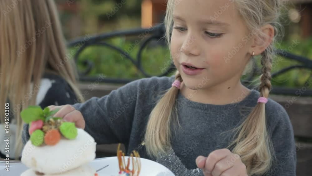 Cute little girl eating cake in the open air cafe Cute little girl eating cake in the open air cafe