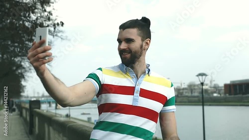 Happy man in colorful shirt doing selfies on boulevards, steadycam shot
 photo