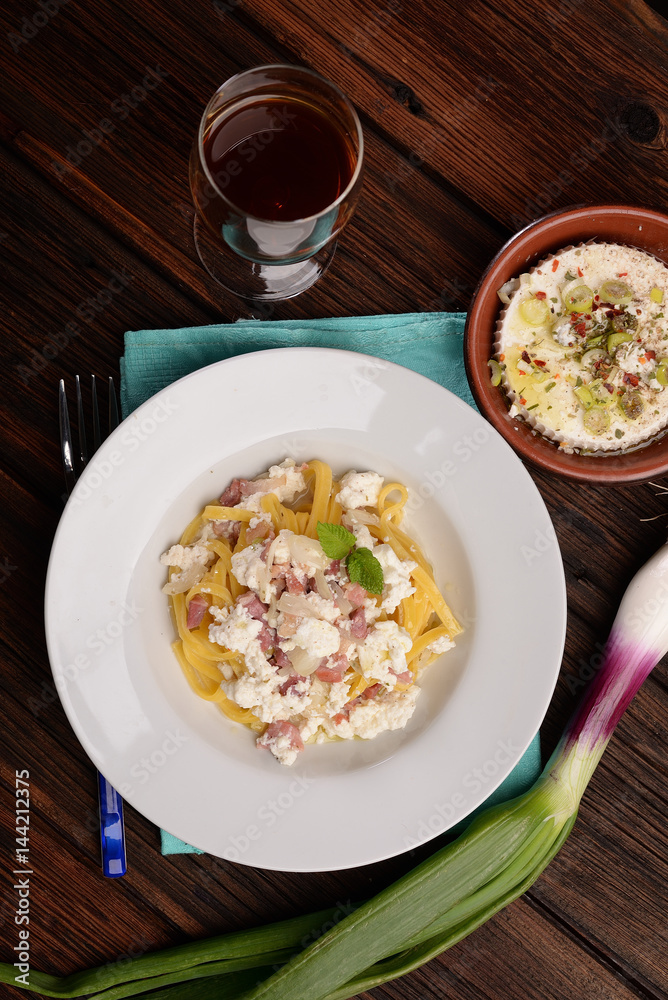 Dish of pasta noodles with cottage cheese bacon and onion shallot
