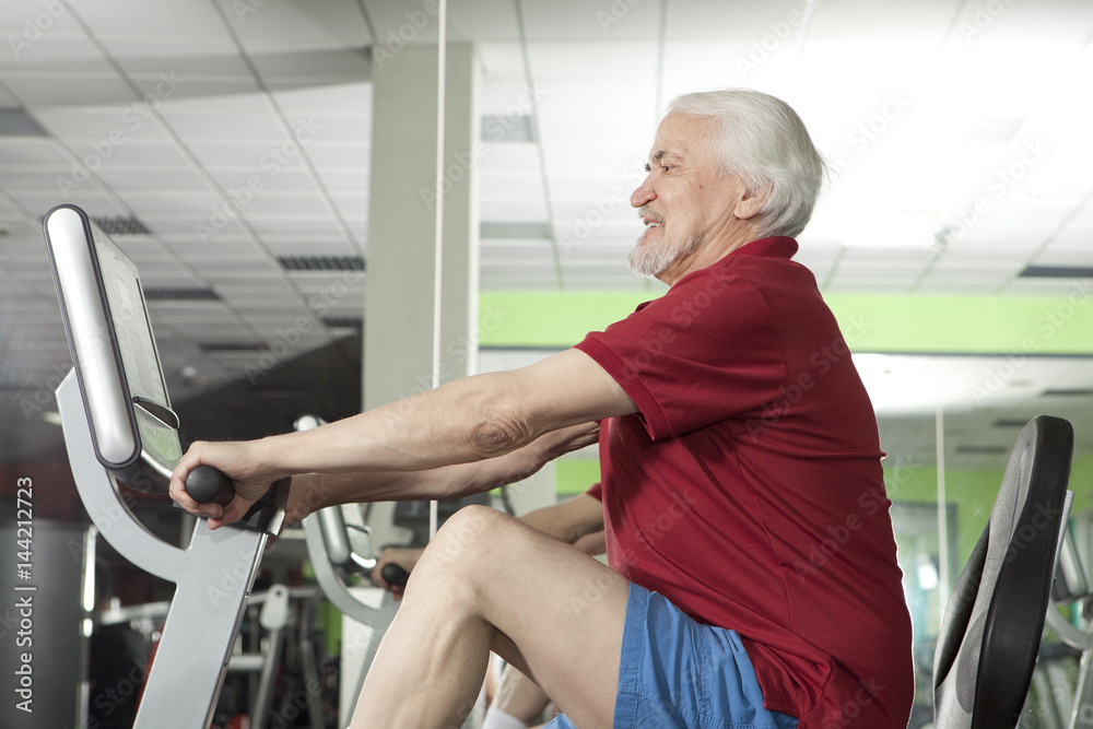 Senior man using trainer in gym