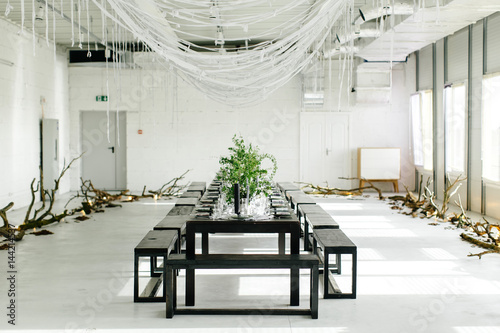 Stylish table, loft. Design room in the loft style. Black table, chairs, dishes, candles. Jars with greens.