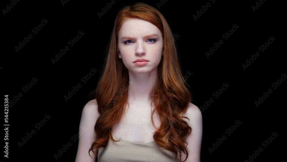 Unhappy dissatisfied young red haired woman looking at camera isolated over black Unhappy dissatisfied young red haired woman looking at camera isolated over black