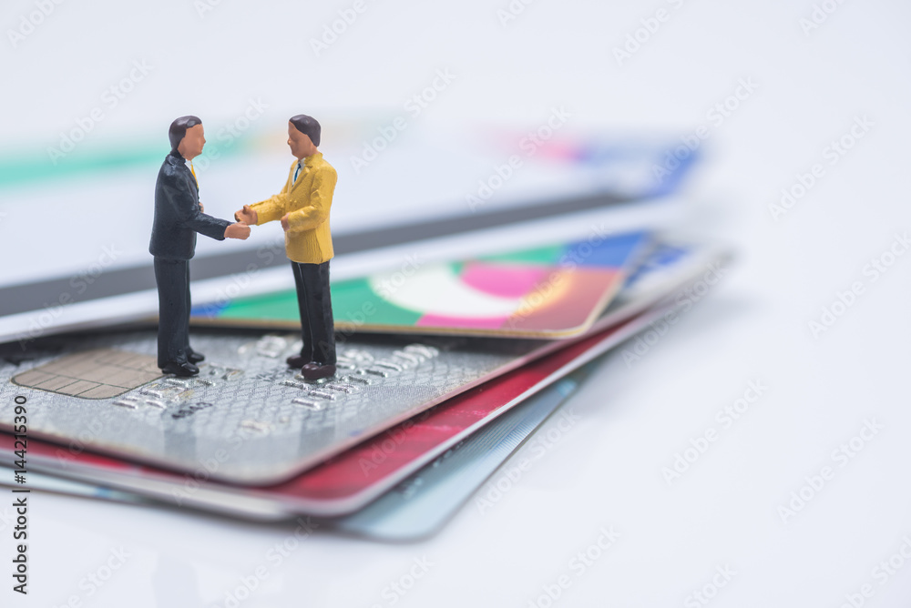 business miniature people shaking hands on credit card stack background business miniature people shaking hands on credit card stack background